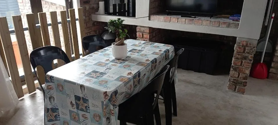 Open-plan living area with dining table, TV, and brick fireplace feature