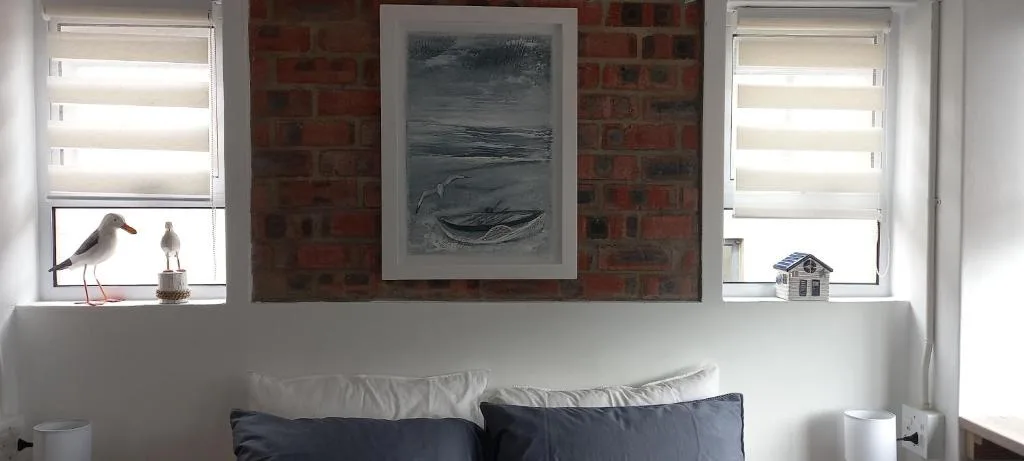 Bright lounge area with white walls, coastal artwork, and comfortable seating