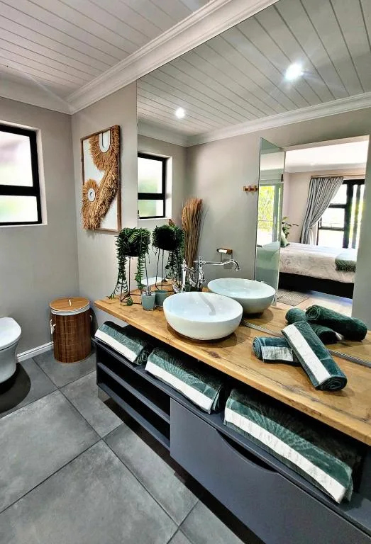 Modern bathroom with dual vessel sinks, wooden countertop, and storage.