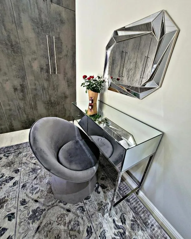 Modern bathroom with gray vessel sink, geometric mirror, and fresh flowers