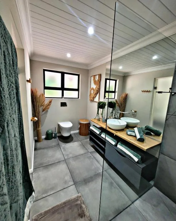 Modern bathroom with double vanity, toilet, and walk-in shower enclosure