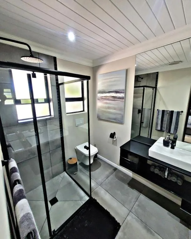 Modern bathroom with walk-in shower, black framing, and white vanity