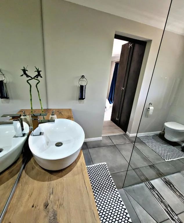Modern bathroom with round white vessel sink on wooden counter and decorative bamboo stems