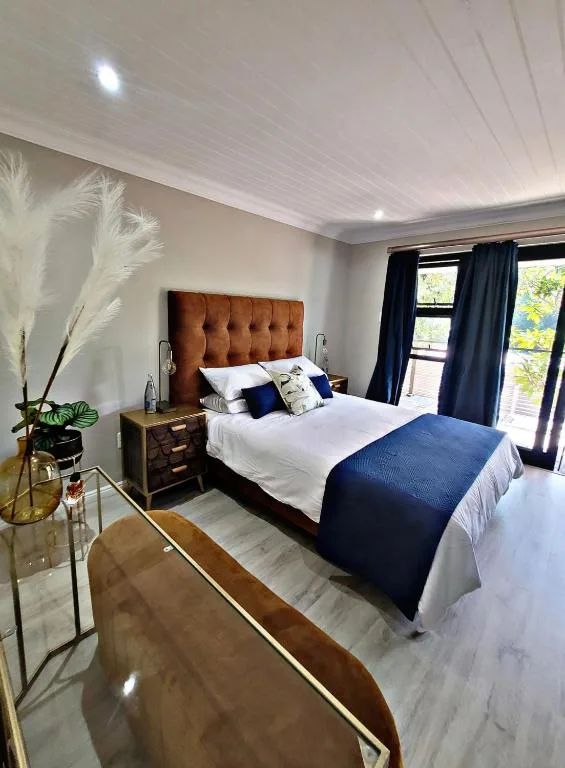 Bright bedroom with terracotta headboard, white linens, and garden views through doors