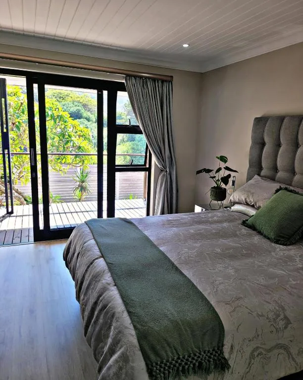 Spacious bedroom with gray upholstered headboard and garden views through sliding doors