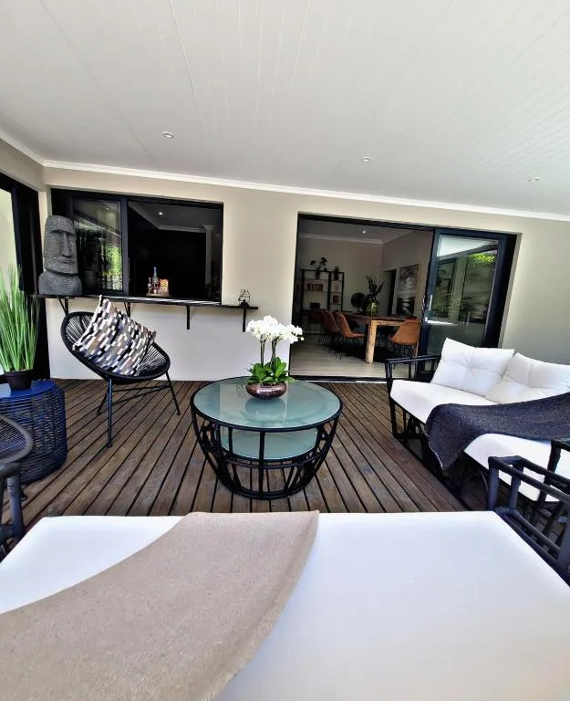 Modern outdoor deck with seating, glass doors, and coastal views