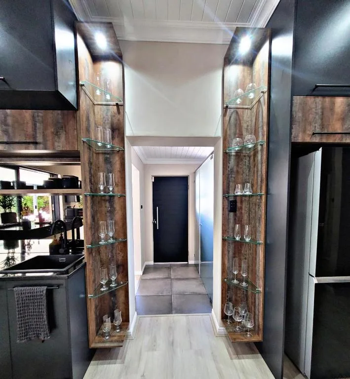 Modern kitchen hallway with rustic wood cabinetry and glass shelving displays