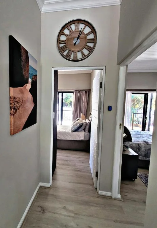 Hallway with wooden clock, framed artwork, and bedroom doorway views