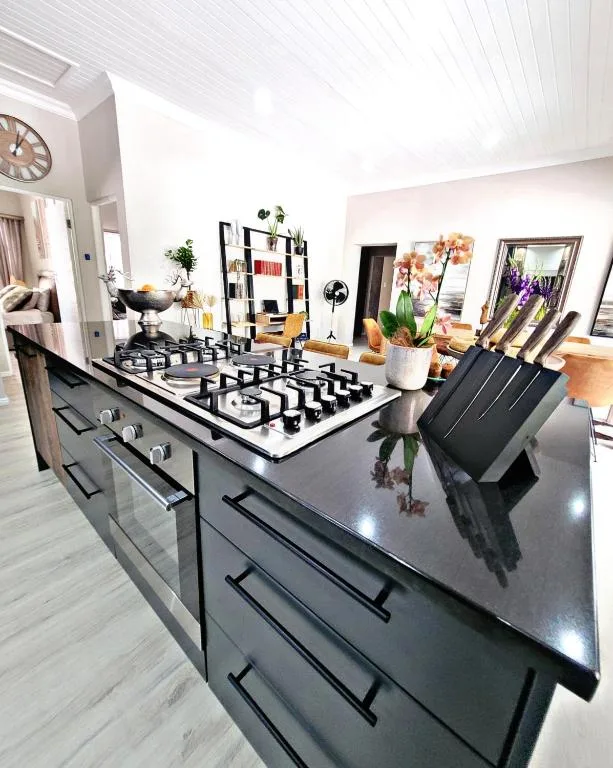 Modern kitchen with gas cooktop, dark cabinetry, and bright open living space