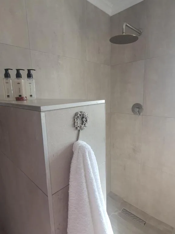 Modern bathroom with rainfall shower, white vanity, and toiletries