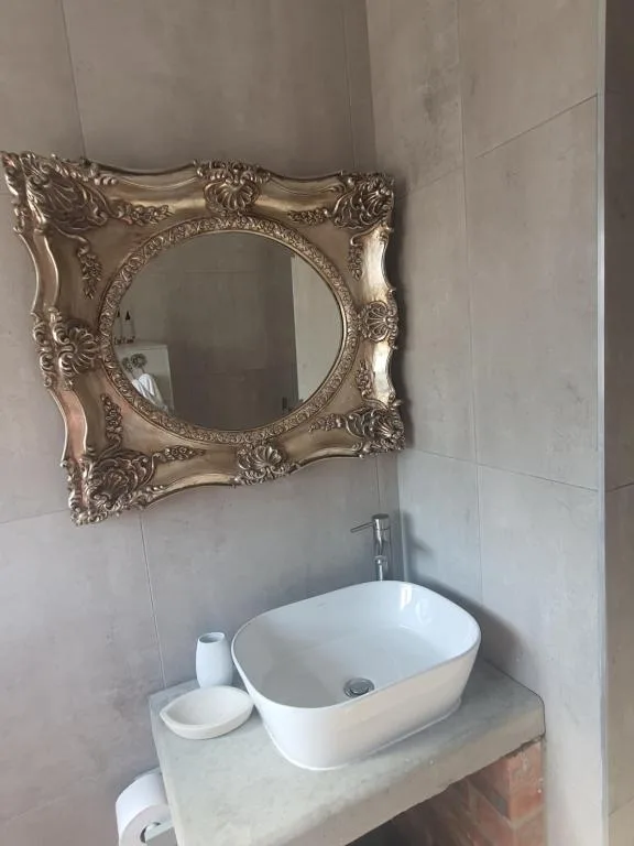 Ornate gold-framed mirror above white vessel sink in bathroom
