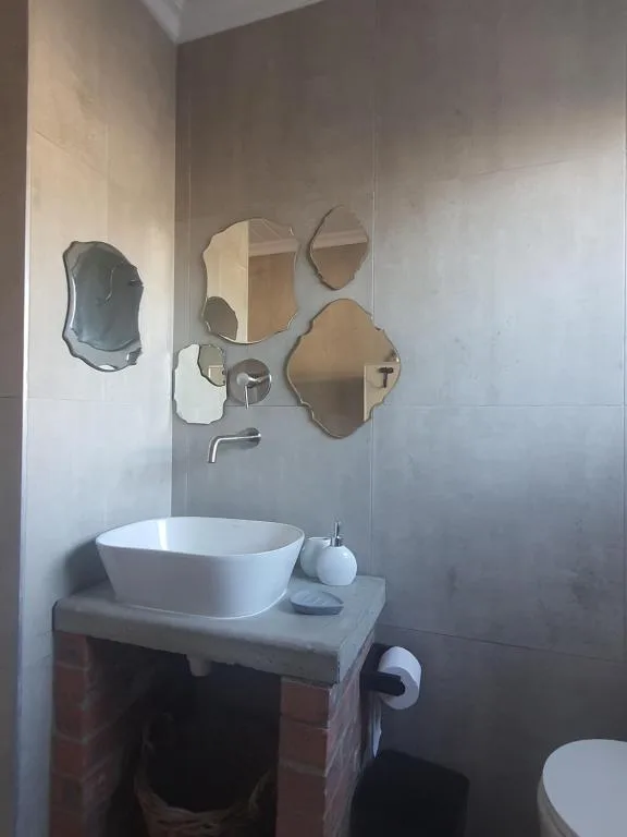 Modern bathroom with round white basin sink and decorative mirrors on wall