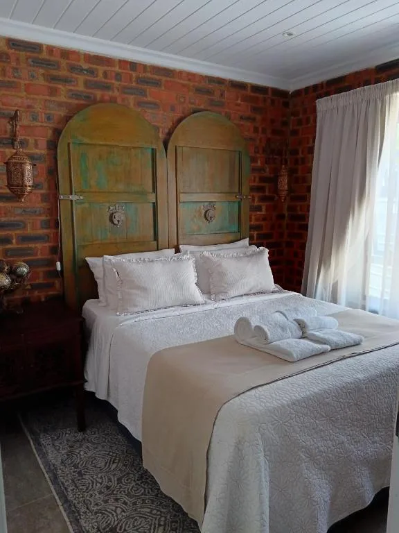 Bedroom with distinctive arched headboard and exposed brick walls, white bedding