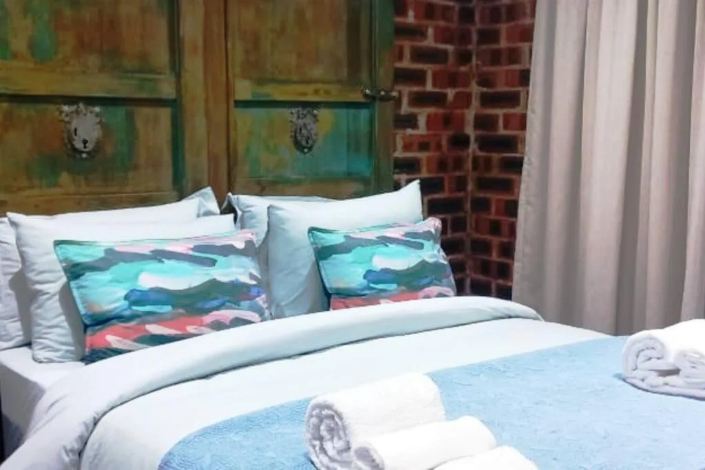 Neatly made bed with colorful patterned pillows and fresh white linens