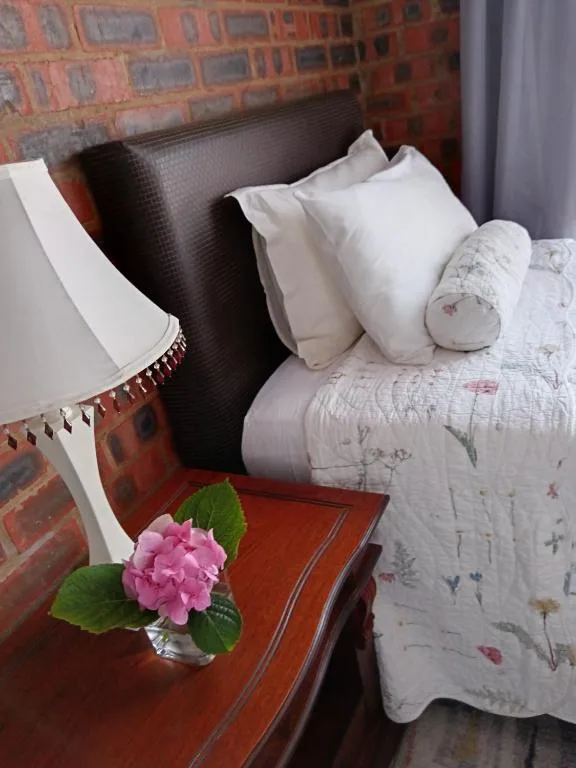 Cozy bedroom with white pillows, floral bedding, and pink flower decoration