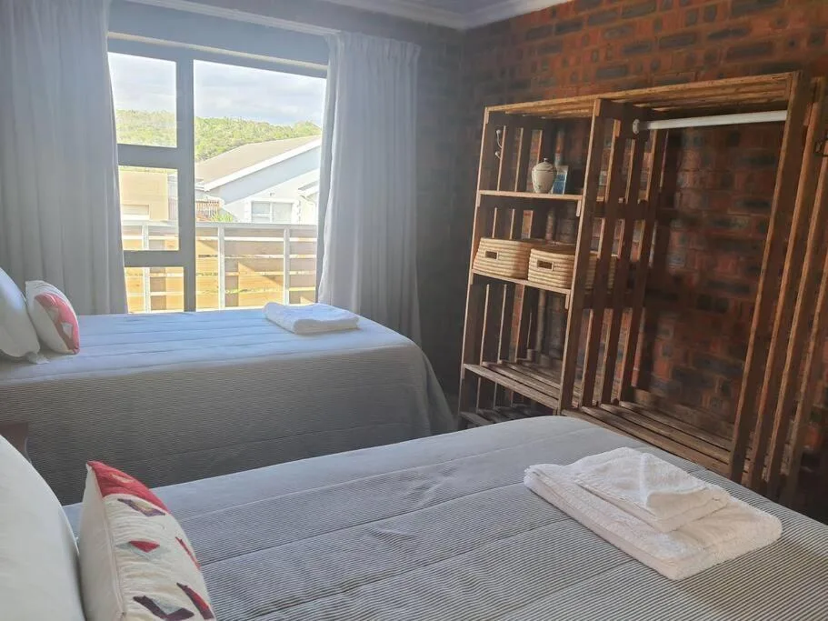 Bright bedroom with two beds, wooden wardrobe, and scenic mountain view windows