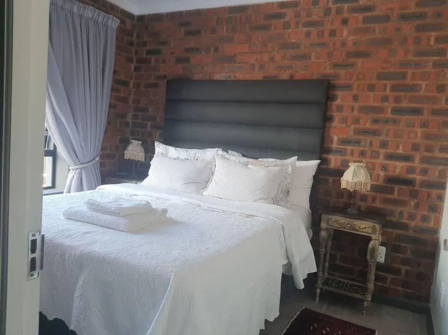 Cozy bedroom with queen bed, exposed brick wall, and white linens