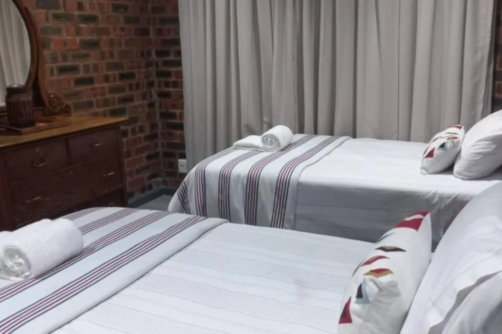 Two twin beds with striped bedding and rolled towels in bright room