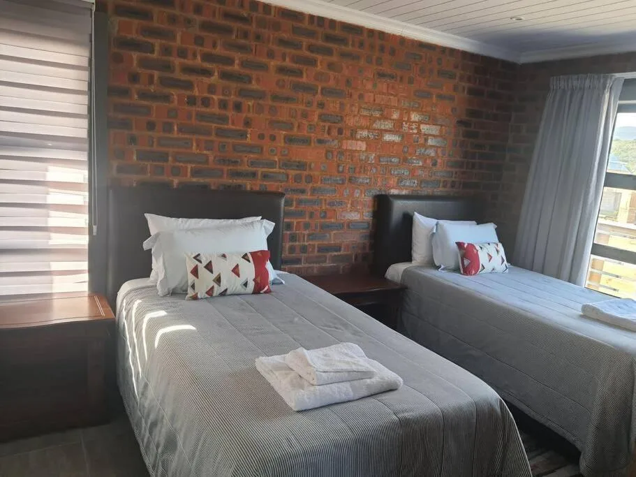 Twin bedroom with exposed brick wall, black headboards, and striped bedding