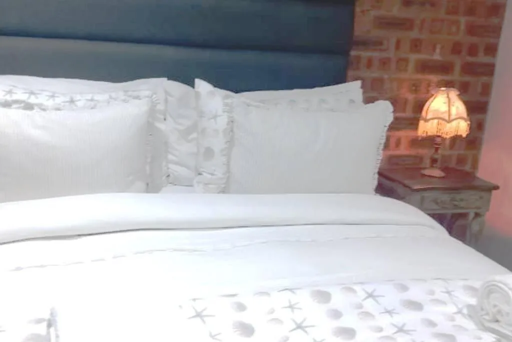 Clean white bedding with pillows and warm bedside lamp in bedroom