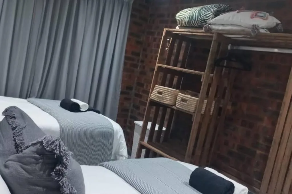 Bedroom with twin beds, wooden wardrobe, and striped curtains