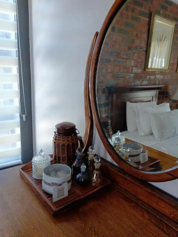 Bedroom with wooden dresser, round mirror, and white bedding visible