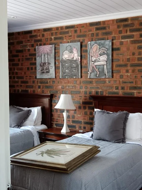 Twin beds with grey bedding against exposed brick wall with art