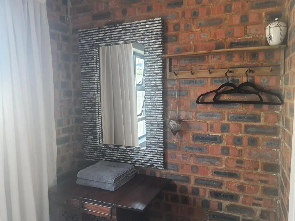 Bathroom vanity with framed mirror against exposed brick wall