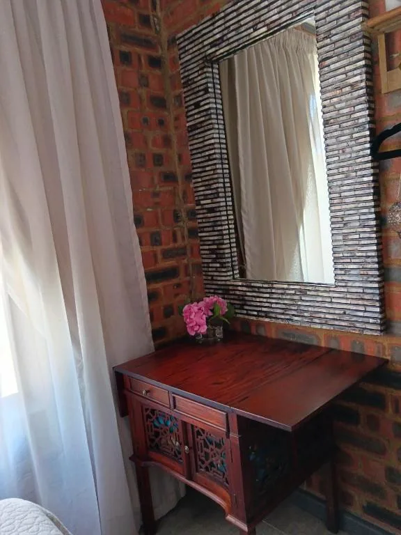 Red wooden vanity with mirror and pink flowers, brick accent wall