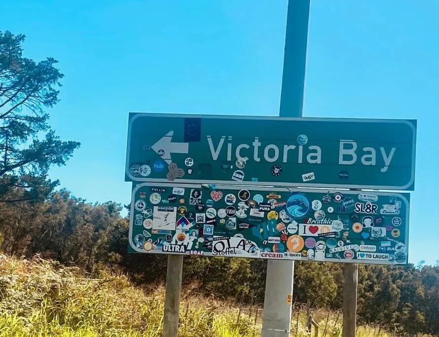 Victoria Bay road sign covered with colorful stickers and local business decals