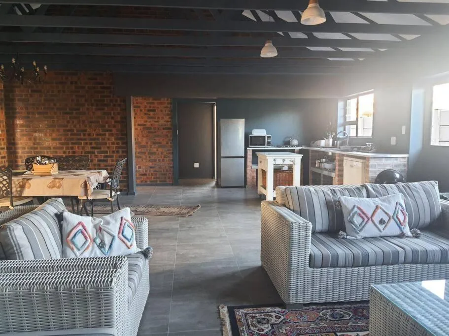 Open-plan lounge with wicker sofas and brick feature walls