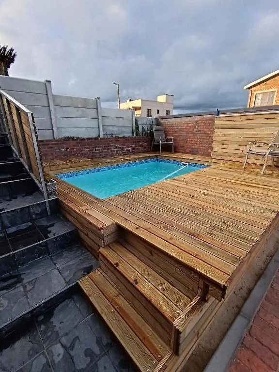 Rectangular swimming pool on wooden deck with brick walls and outdoor seating