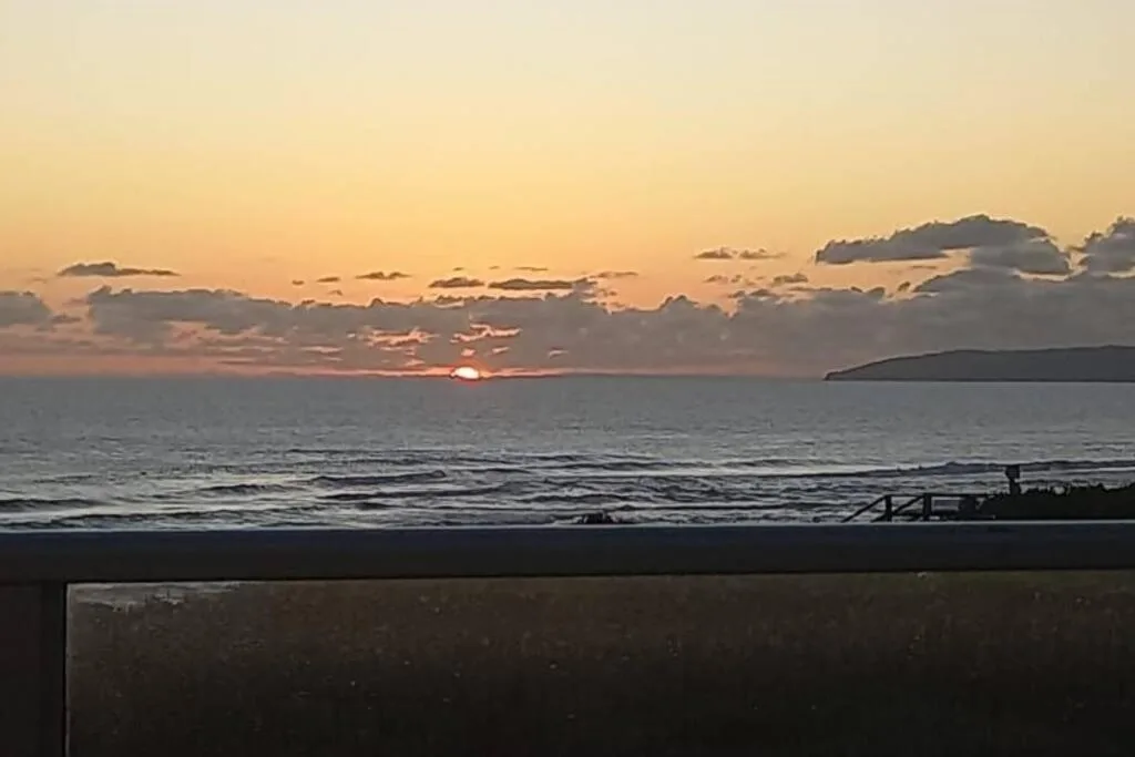 Sunset over ocean with mountains and jetty visible from deck