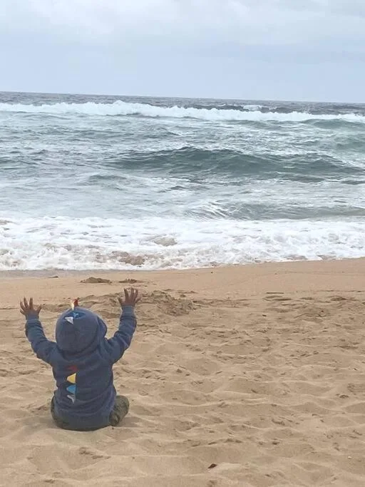 Golden beach with rolling ocean waves and a child enjoying the seaside