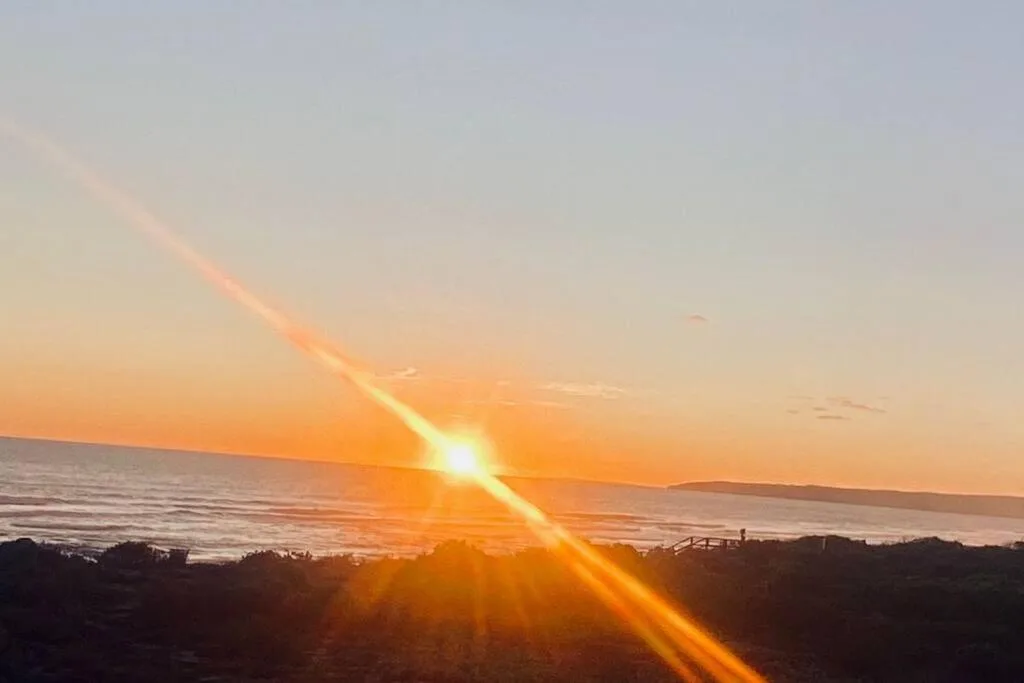 Stunning ocean sunset with golden light over coastal waters and hills