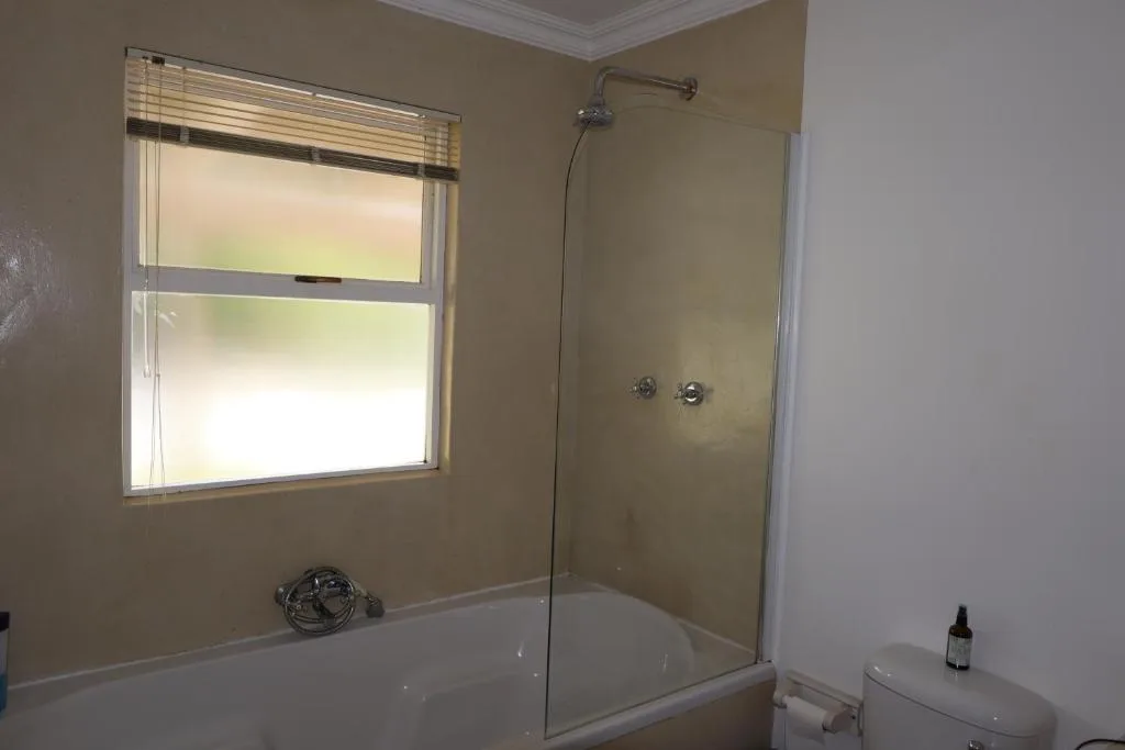 Bathroom with bathtub, glass shower enclosure, and bright window