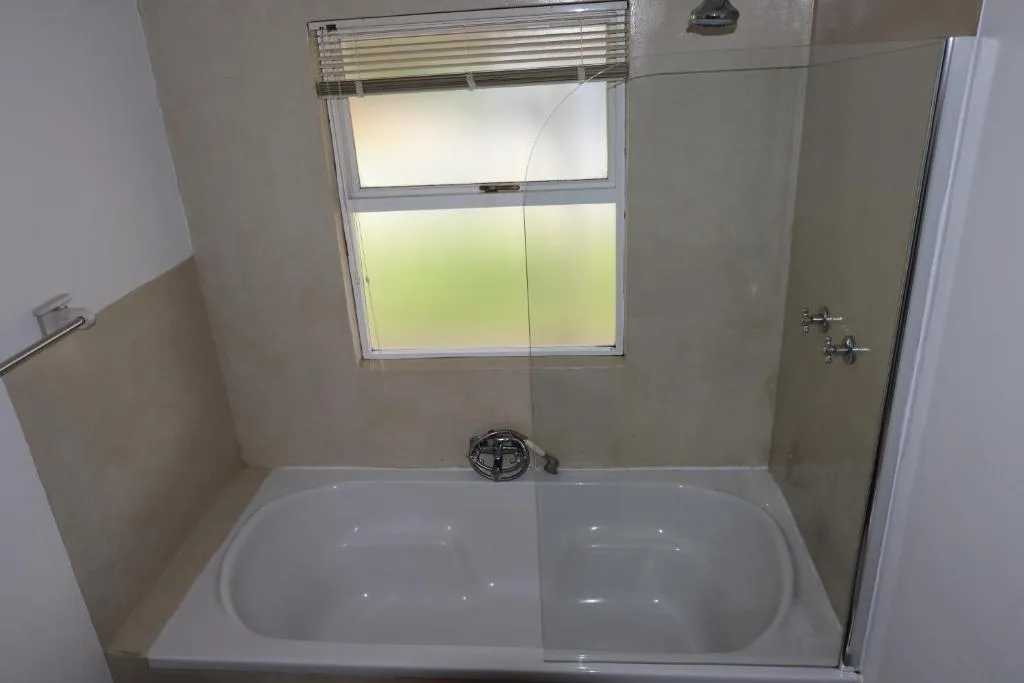 Modern bathroom with double basin tub and window overlooking garden area