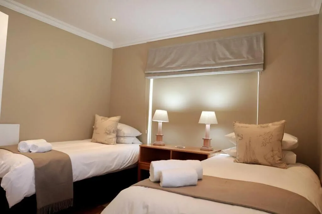 Twin bedroom with neutral decor, bedside lamps, and plush pillows