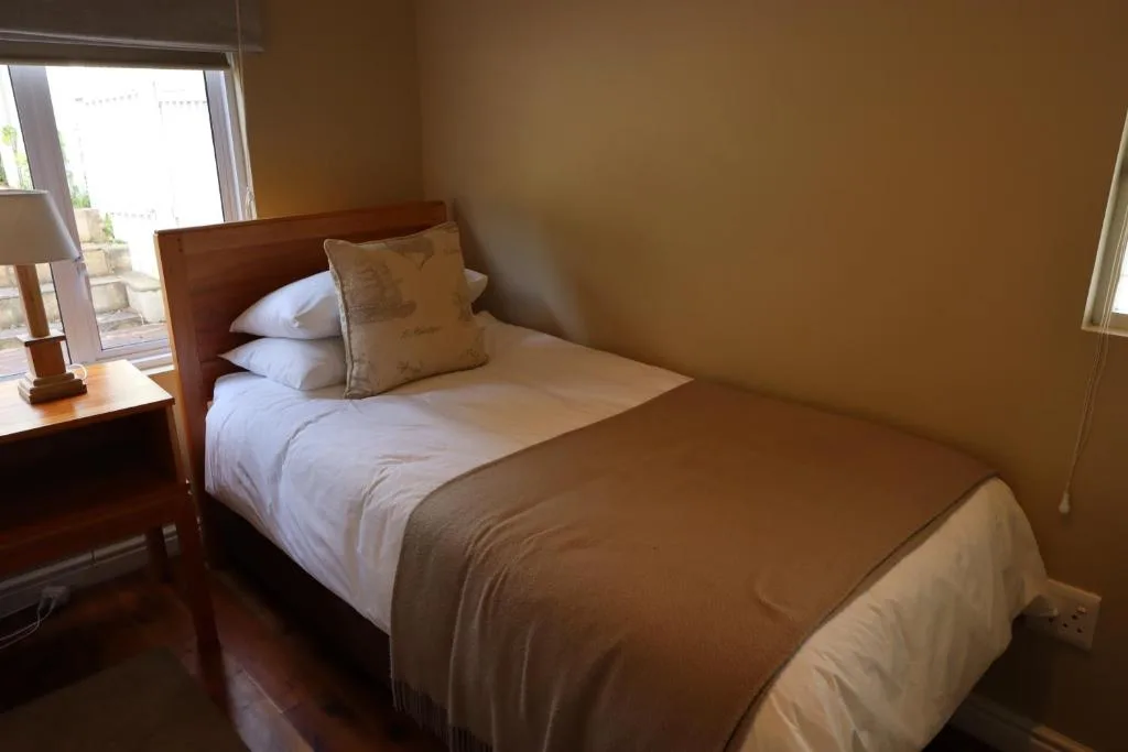Warm bedroom with wooden bed frame and white bedding beside window