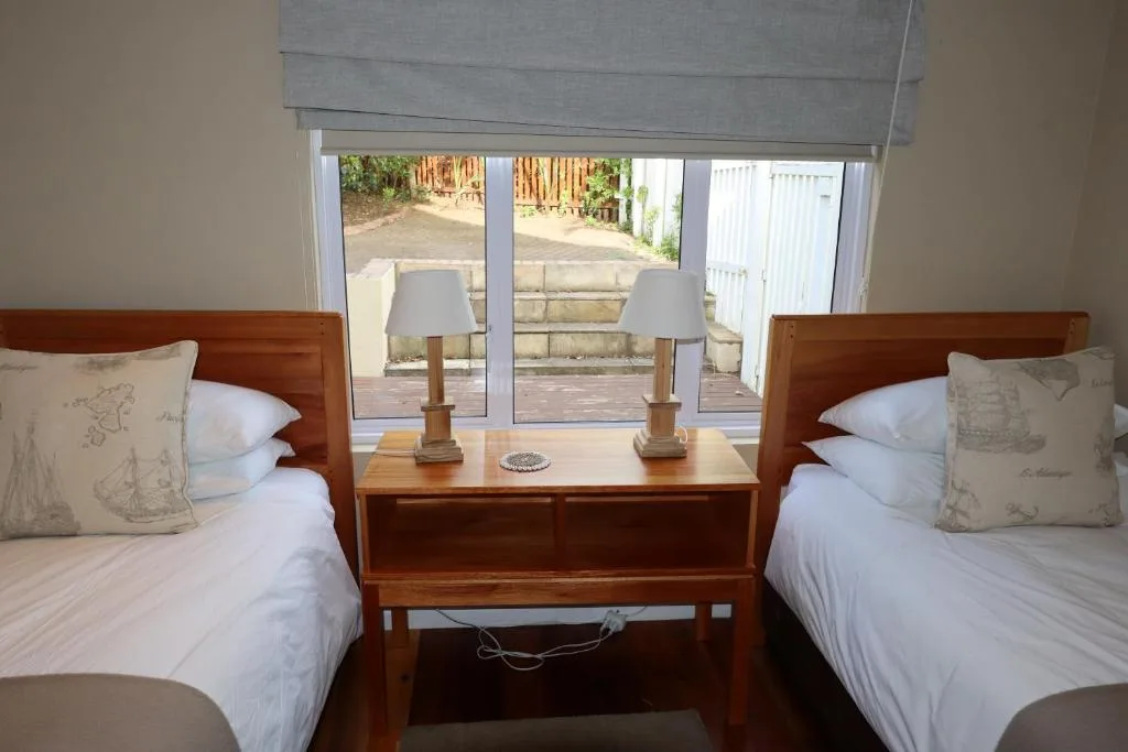 Twin bedroom with wooden headboards overlooking garden patio area