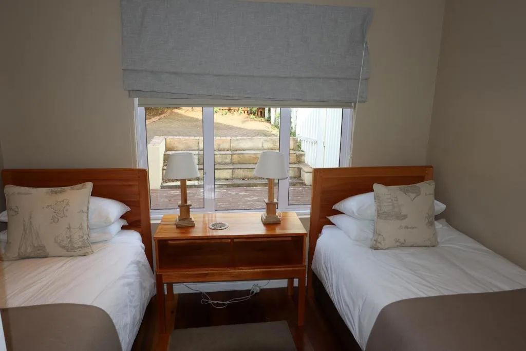 Twin bedroom with wooden beds, white linens, and deck view through French doors