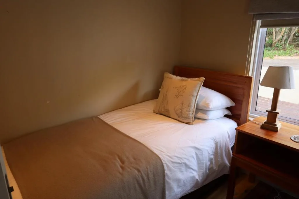 Bedroom with single bed, wooden headboard, and deck access