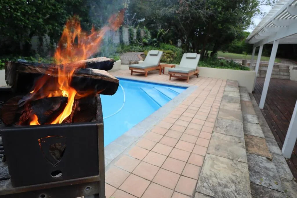 Outdoor braai with pool, loungers and covered patio area