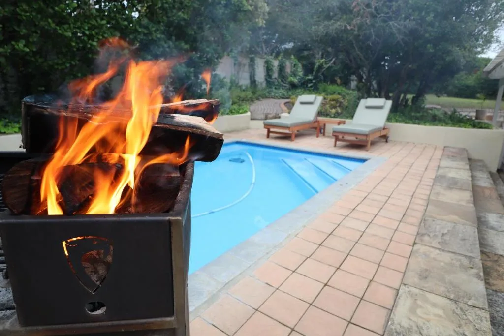Braai fire pit with swimming pool and loungers in background