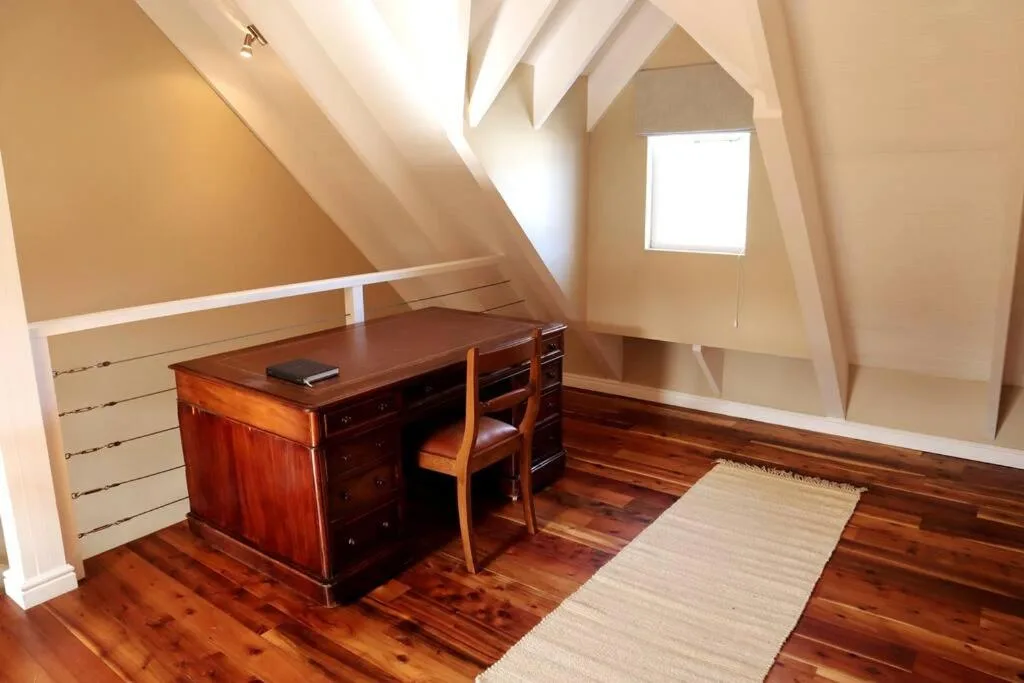 Attic workspace with wooden desk, chair, and built-in storage shelving