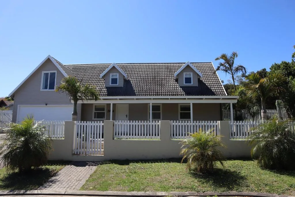 Contemporary home with white railings and dormer windows, palm trees flanking entrance