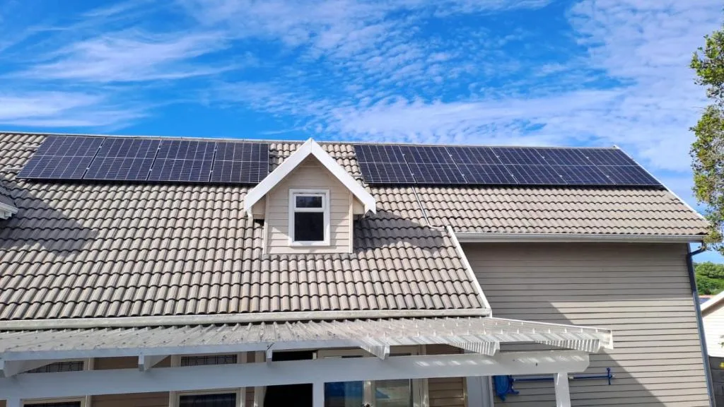 Modern house with solar panels and white dormer window under blue sky