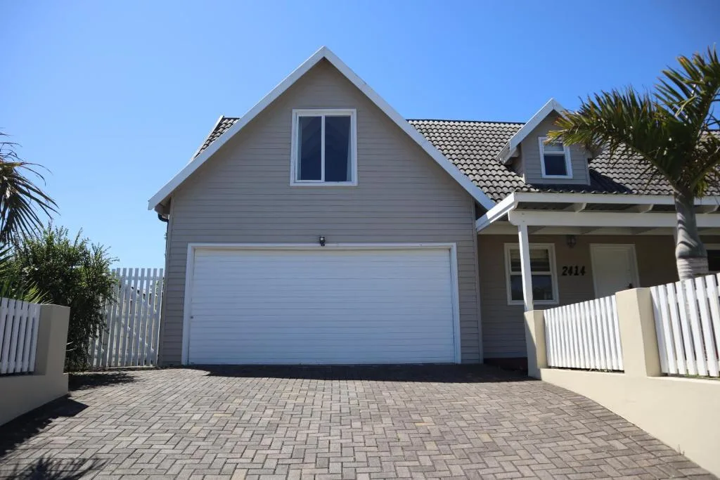 Modern grey house with white garage door and white fence entry