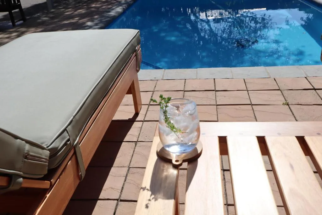 Sparkling blue swimming pool with lounger and refreshing drink poolside