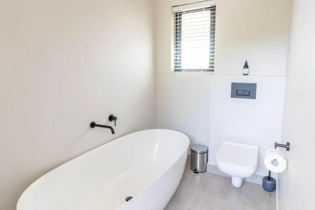 Modern bathroom with freestanding white bathtub and wall-mounted black fixtures